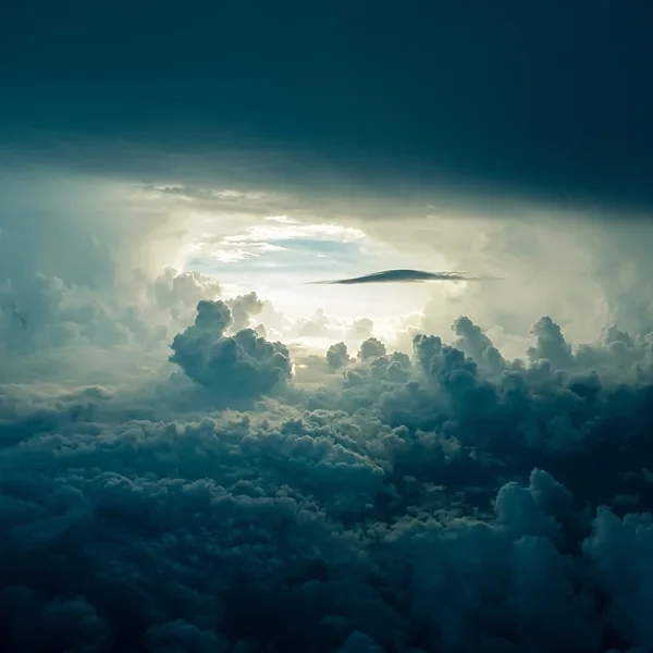 Zicht boven een wolkendek met licht dat door de wolken breekt