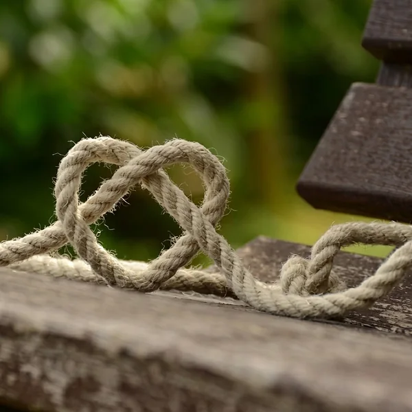 Touw dat tot een hart is geknoopt op een houten bank